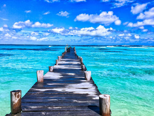 picture of a long dock extending into a blue green ocean