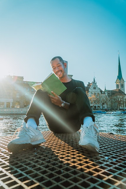 Man laughing and reading by a pretty river